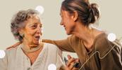 A young woman and an old woman look at each other smiling.