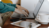 A therapist types on a laptop wondering about what it means to be HIPAA compliant as a therapist