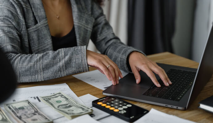 A therapist uses a laptop and calculator to plan her budget and financial goals for the year ahead