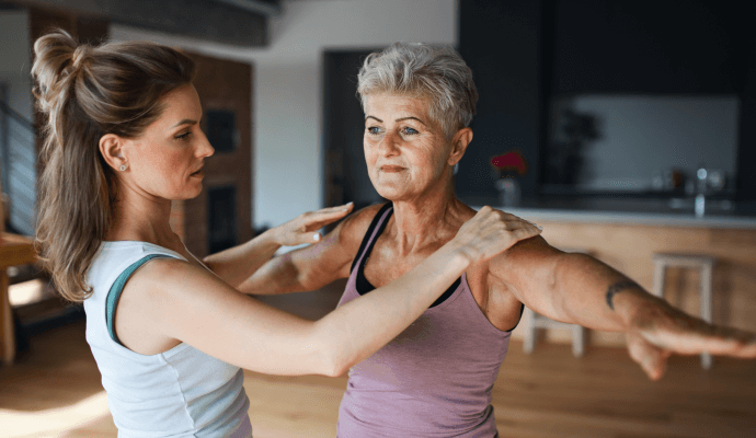 A physical therapist treats a client as they spread their arms horizontally. After treatment, the physical therapist will need to bill the client's insurance using the correct physical therapy billing units, physical therapy billing codes, and reimbursement rates, to ensure prompt and accurate insurance payment.